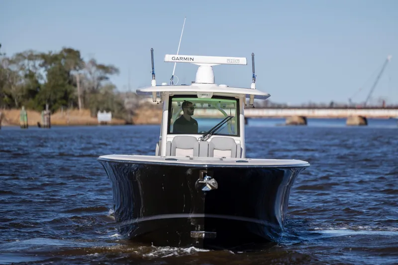 Slide: The Image of 2019 Scout 355 LXF boat cruising on a river with a bridge in the background. - 11