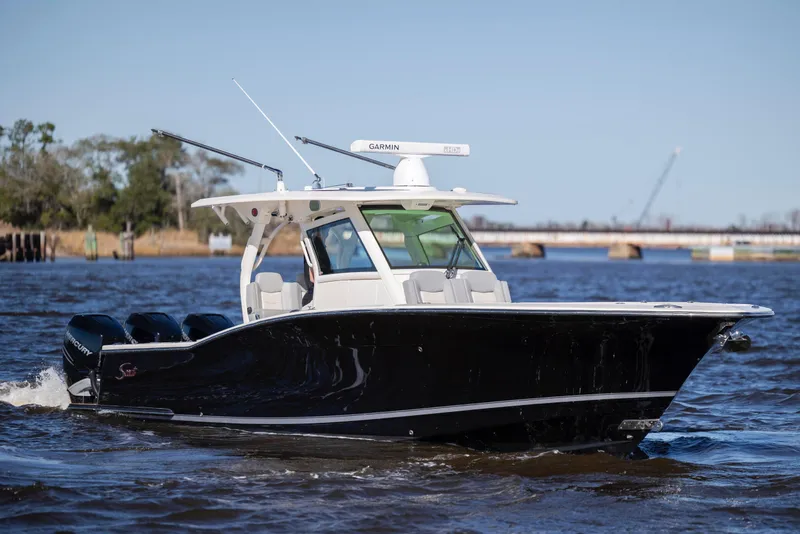 Slide: The Image of 2019 Scout 355 LXF boat cruising on a river with clear skies. - 12