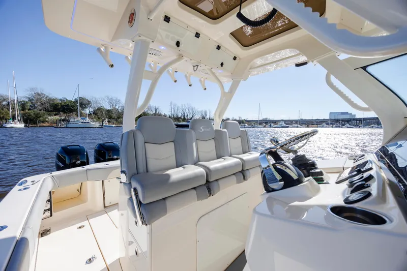 Slide: The Image of 2019 Scout 355 LXF boat interior with luxurious seating and modern controls on a sunny day. - 21