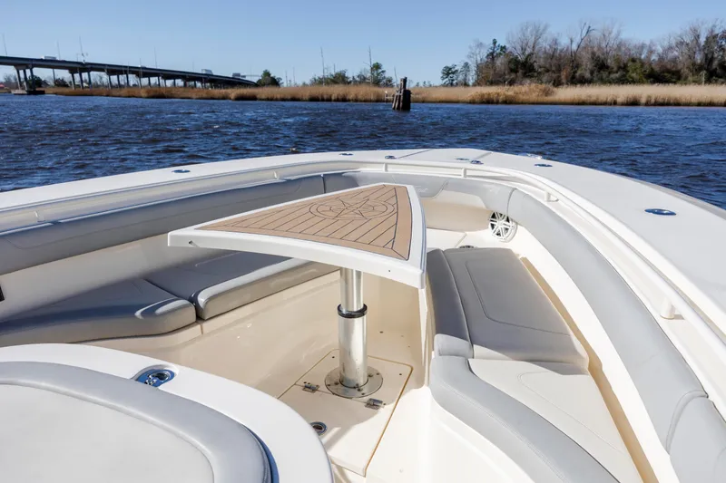 Slide: The Image of 2019 Scout 355 LXF boat interior with seating and table on calm water. - 30