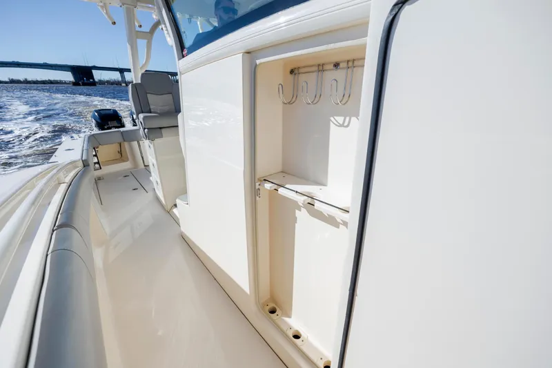 Slide: The Image of 2019 Scout 355 LXF boat interior with rod holders, cruising on water. - 36