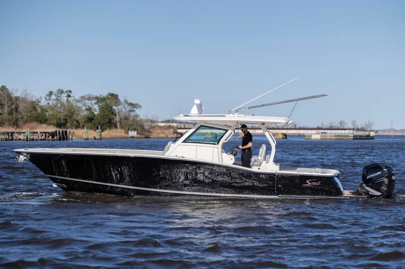 Slide: The Image of 2019 Scout 355 LXF boat cruising on a sunny day with a person onboard. - 9