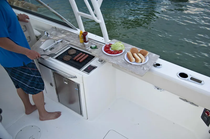 Slide: The Image of Manufacturer Provided Image: Man grilling on a 2016 Boston Whaler 270 Vantage boat with food prepared. - 25