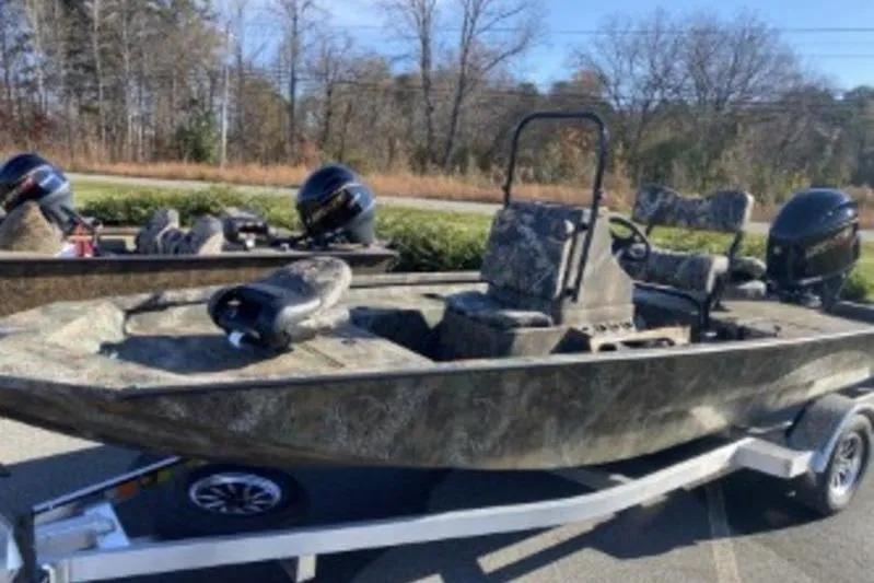 The Image of 2026 G3 Bay 19 GX boat on trailer, camo design, dual outboard motors. - 0