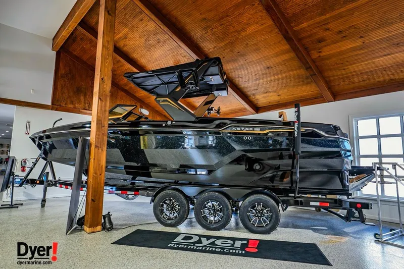 The Image of 2026 MasterCraft XStar 25 boat on trailer in showroom, featuring sleek black design. - 1