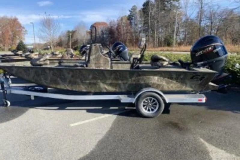 Slide: The Image of 2026 G3 Bay 19 GX boat on trailer, parked outdoors, with trees in background. - 9