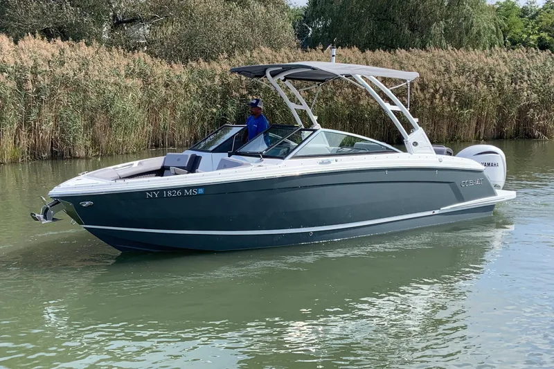 Slide: The Image of 2022 Cobalt R6 Outboard boat cruising on a calm river with lush greenery. - 1