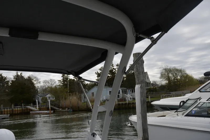 Slide: The Image of 2022 Cobalt R6 Outboard boat docked near waterfront homes under cloudy sky. - 24