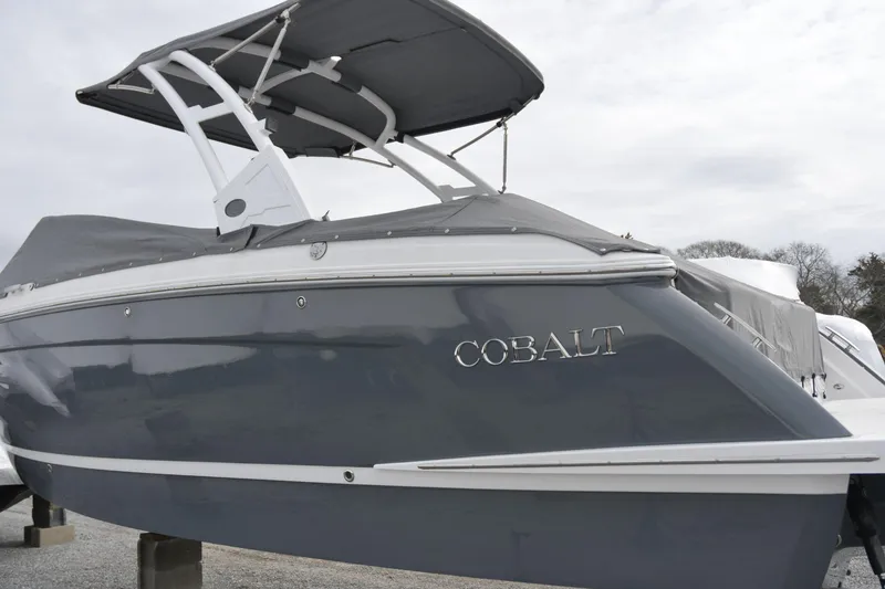 Slide: The Image of 2022 Cobalt R6 Outboard boat with gray cover and canopy, parked on stands. - 27
