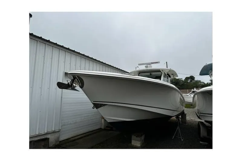 The Image of 2014 Boston Whaler 370 Outrage boat on dry dock near a metal building. - 0