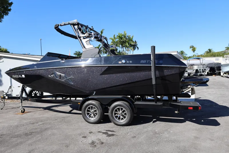 Slide: The Image of 2025 ATX Surf Boats 22 Type-S on trailer, sleek black design, parked outdoors. - 4