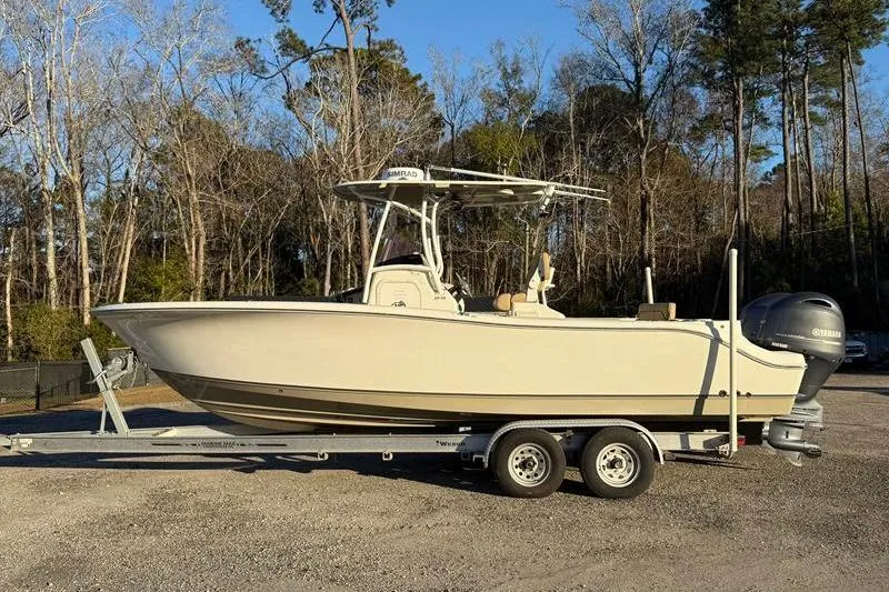 The Image of 2019 NauticStar 25 XS boat on trailer, parked outdoors with trees in background. - 1