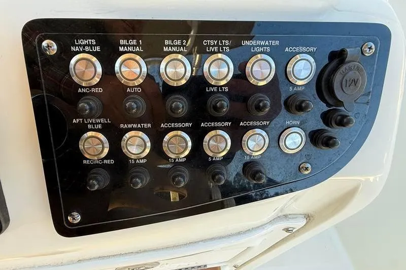 Slide: The Image of Control panel of a 2019 NauticStar 25 XS boat with various switches and buttons. - 16