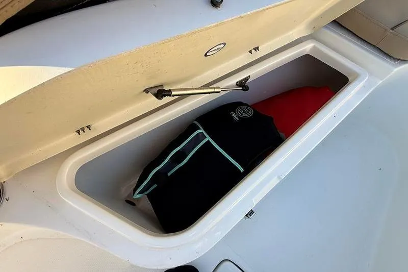 Slide: The Image of Open storage compartment on 2019 NauticStar 25 XS boat with life jacket inside. - 24