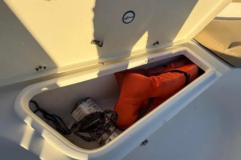 Slide: The Image of Storage compartment on 2019 NauticStar 25 XS boat with life jacket and supplies. - 25