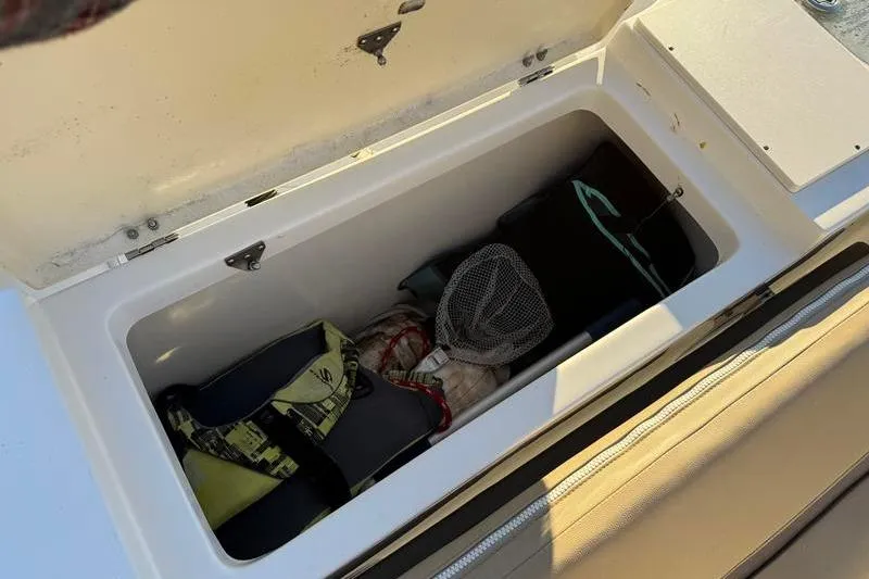 Slide: The Image of Open storage compartment on 2019 NauticStar 25 XS boat with gear inside. - 32