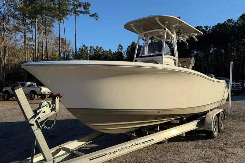 Slide: The Image of 2019 NauticStar 25 XS boat on trailer, parked outdoors with trees in background. - 7