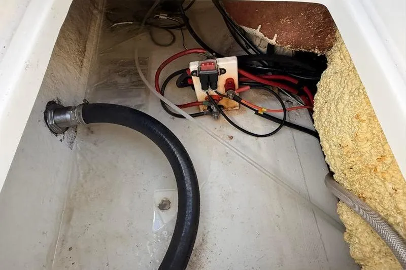 Slide: The Image of 2019 NauticStar 25 XS boat wiring and plumbing components in storage compartment. - 9