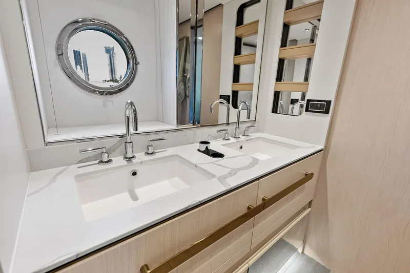 Slide: The Image of Luxurious bathroom with dual sinks on 2021 Azimut Fly 78 yacht, featuring modern fixtures and porthole window. - 97