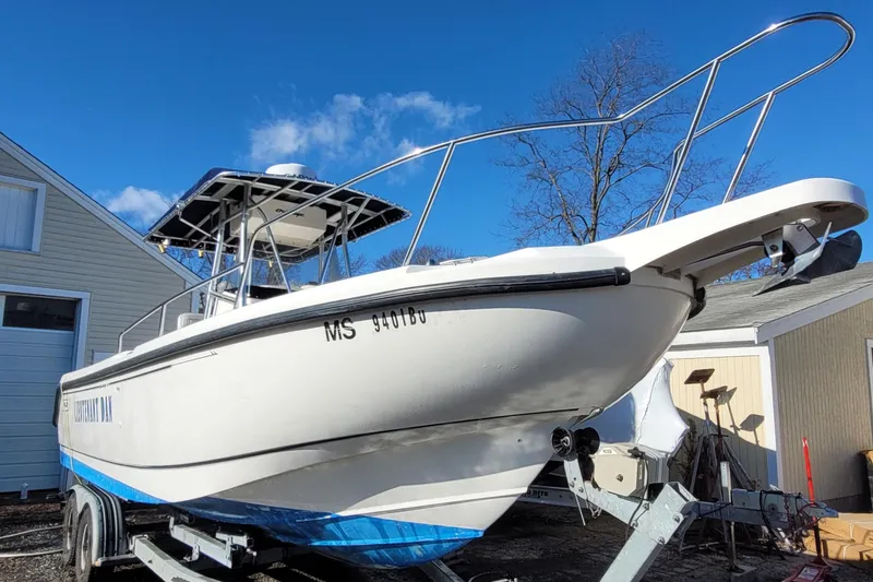 Slide: The Image of 1999 Boston Whaler 26 Outrage boat on trailer, parked outdoors under clear blue sky. - 0