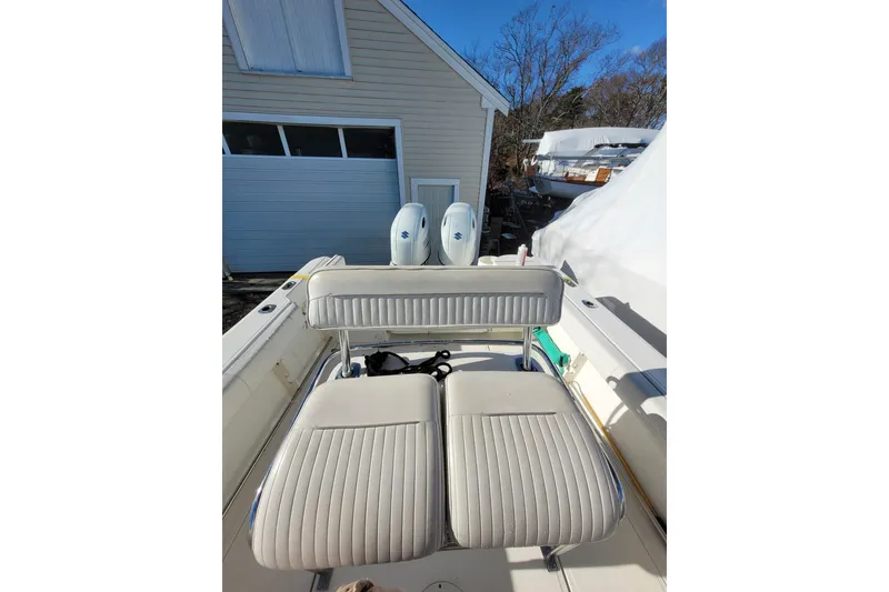 Slide: The Image of 1999 Boston Whaler 26 Outrage boat with dual engines and cushioned seating, parked outdoors. - 6