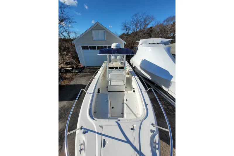 Slide: The Image of 1999 Boston Whaler 26 Outrage boat docked near a garage under clear blue sky. - 8