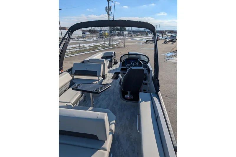 Slide: The Image of 2026 Sylvan G5 CLZ boat interior with seating and steering console, parked outdoors. - 7