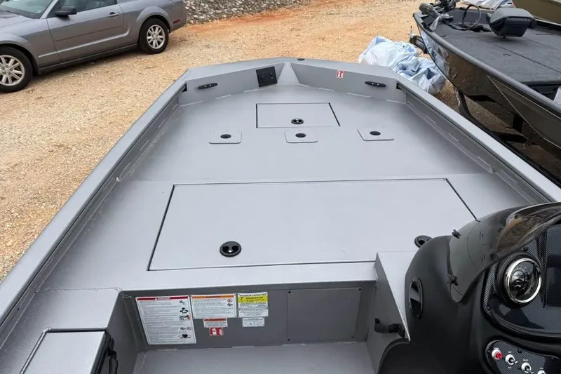 Slide: The Image of 2026 Lowe Outlet 20 boat interior with storage compartments, parked on gravel. - 11