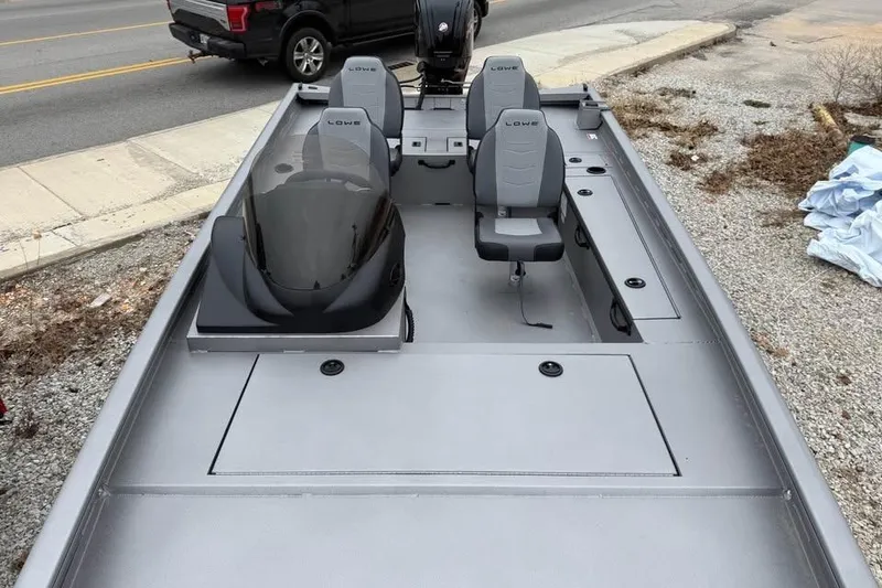 Slide: The Image of 2026 Lowe Outlet 20 boat with gray seating and console, parked near a road. - 13
