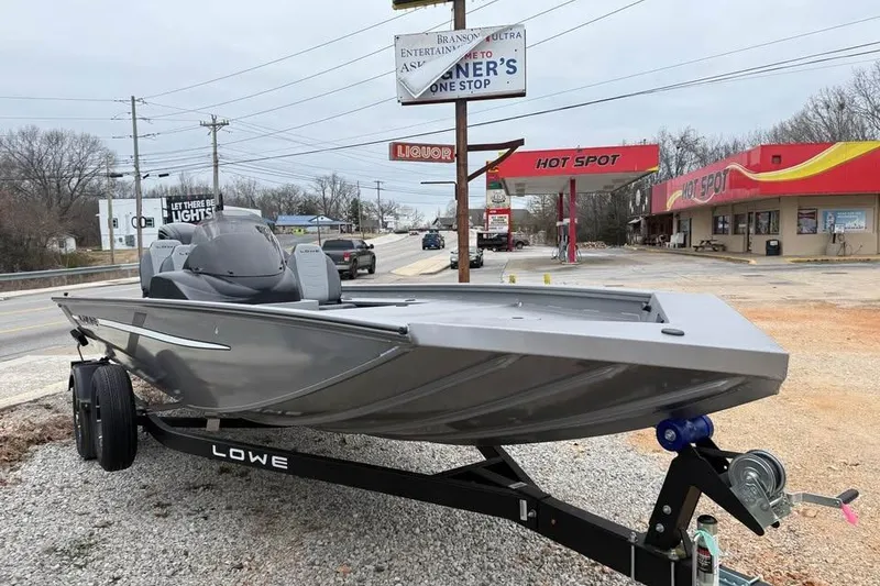 Slide: The Image of 2026 Lowe Outlet 20 boat on trailer near roadside shops and signs. - 3
