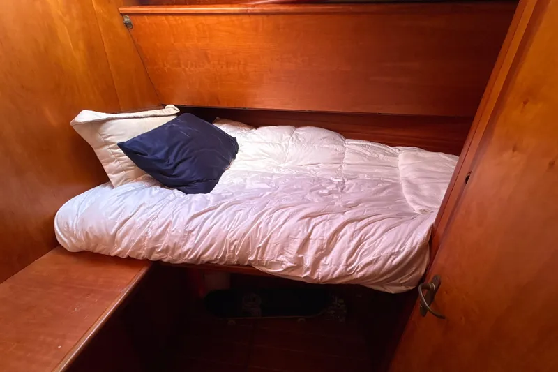 Slide: The Image of Cozy cabin bed in 2001 North Wind 56 yacht, featuring wooden interior and plush bedding. - 22