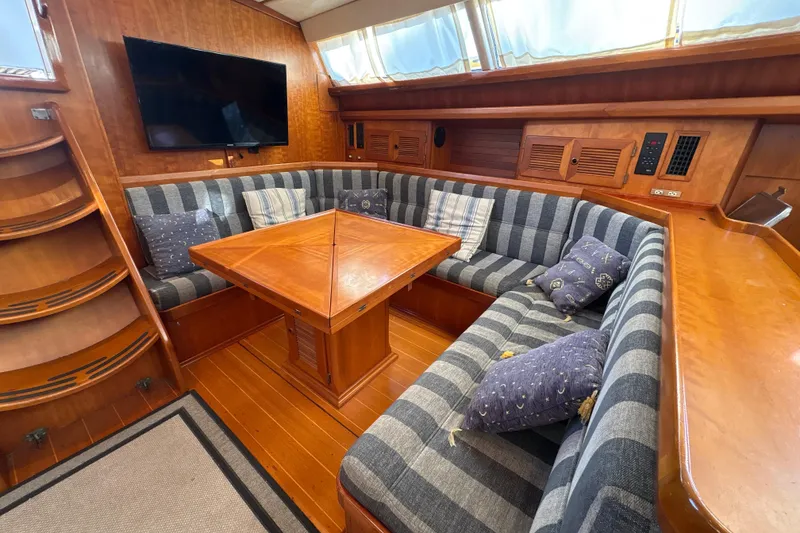Slide: The Image of Luxurious North Wind 56 yacht interior with striped seating, wooden table, and mounted TV, 2001 model. - 26