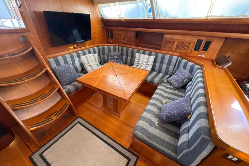 Slide: The Image of Luxurious North Wind 56 yacht interior with striped seating, wooden table, and mounted TV, 2001 model. - 29