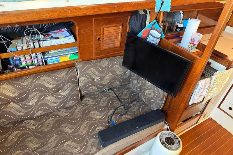 Slide: The Image of Cozy interior of 1989 Nonsuch 30 Ultra sailboat with books, TV, and patterned seating. - 14
