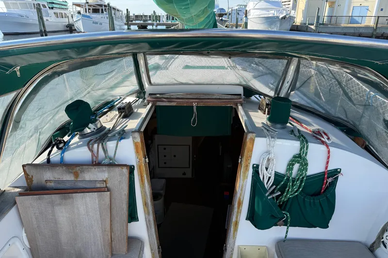 Slide: The Image of 1989 Nonsuch 30 Ultra sailboat cockpit with green canvas and docked marina view. - 16