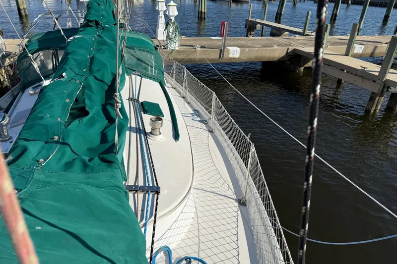 Slide: The Image of 1989 Nonsuch 30 Ultra sailboat docked, featuring green sail cover and marina setting. - 20