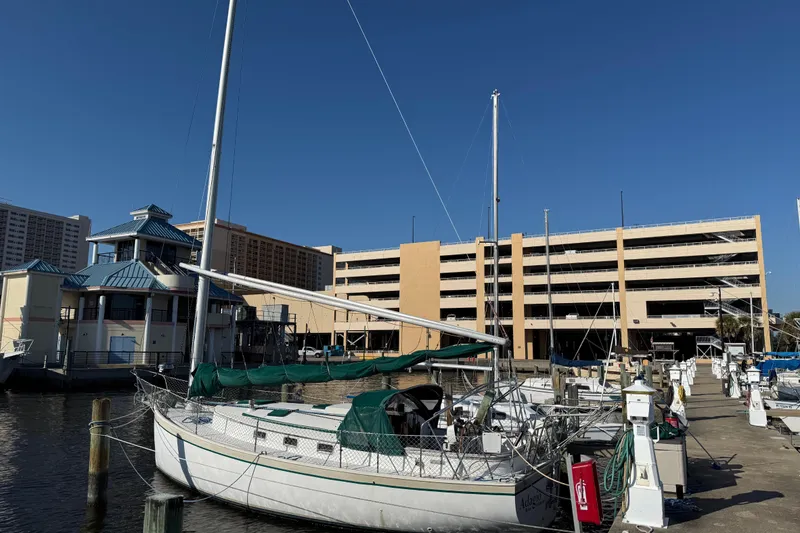 Slide: The Image of 1989 Nonsuch 30 Ultra sailboat docked at marina with buildings in background. - 6