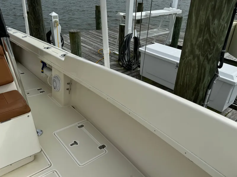 Slide: The Image of 2004 Intrepid 32 Cuddy boat docked, showcasing clean deck and storage compartments. - 21