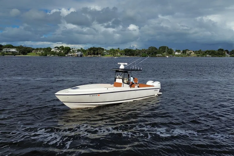 Slide: The Image of 2004 Intrepid 32 Cuddy boat cruising on a scenic waterway under cloudy skies. - 3
