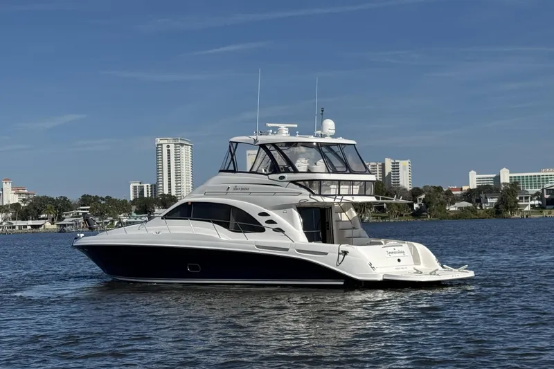 Slide: The Image of 2007 Sea Ray 58 Sedan Bridge yacht on calm water with cityscape background. - 1