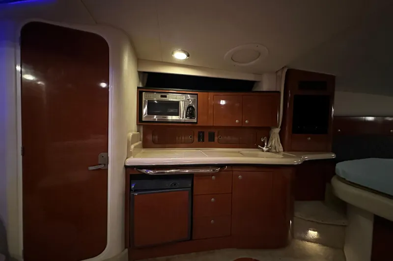 Slide: The Image of Interior of 2005 Sea Ray 320 Sundancer with kitchenette, microwave, and wooden cabinetry. - 14
