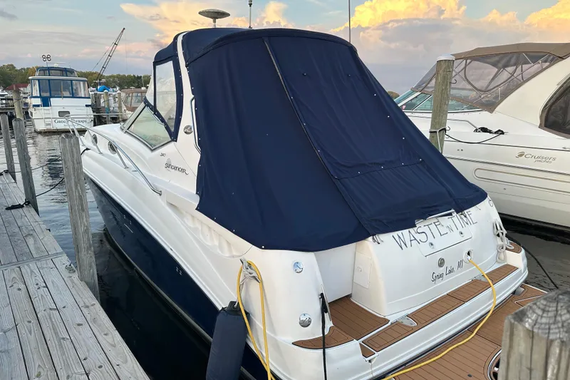 Slide: The Image of 2005 Sea Ray 320 Sundancer docked with blue cover, scenic marina background. - 2