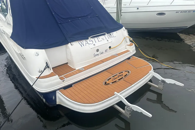 Slide: The Image of 2005 Sea Ray 320 Sundancer docked, featuring teak swim platform and navy blue cover. - 3