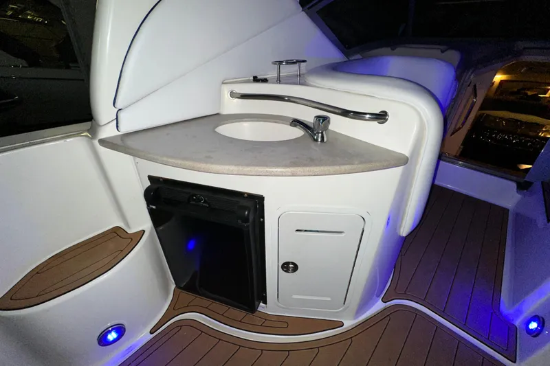 Slide: The Image of 2005 Sea Ray 320 Sundancer boat interior with sink, cabinet, and ambient blue lighting. - 6