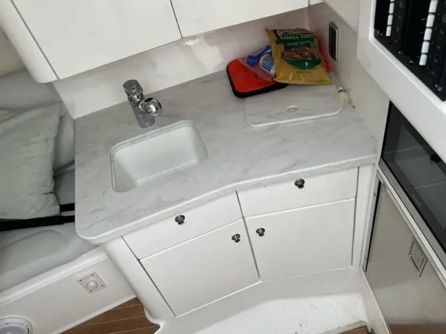 Slide: The Image of Compact kitchen area in a 2018 Intrepid 375 Walkaround boat with sink and storage cabinets. - 20