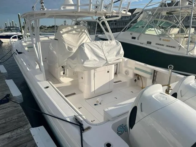 Slide: The Image of 2018 Intrepid 375 Walkaround boat docked at marina, covered seating area, twin outboard engines. - 8