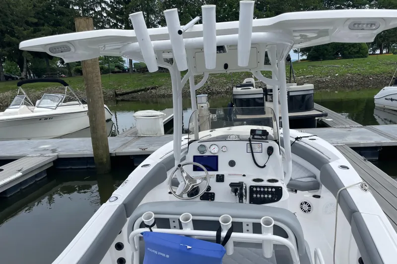 Slide: The Image of 2024 NauticStar 222L Offshore boat docked, featuring a modern helm and fishing rod holders. - 3