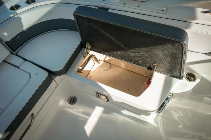 Slide: The Image of 2021 Chaparral 280 OSX boat interior storage compartment open, showcasing seating and cup holders. - 22