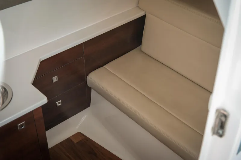 Slide: The Image of 2021 Chaparral 280 OSX interior with beige seating and wooden cabinetry. - 24