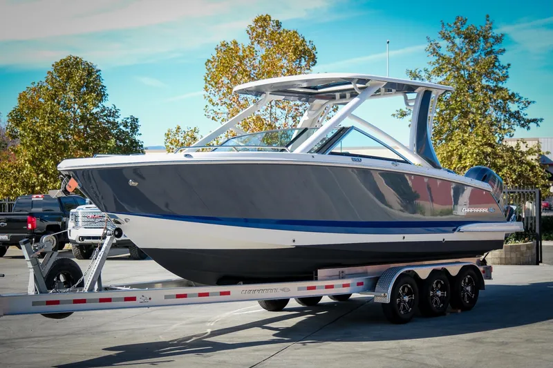 Slide: The Image of 2021 Chaparral 280 OSX boat on a trailer, parked outdoors with trees in the background. - 4